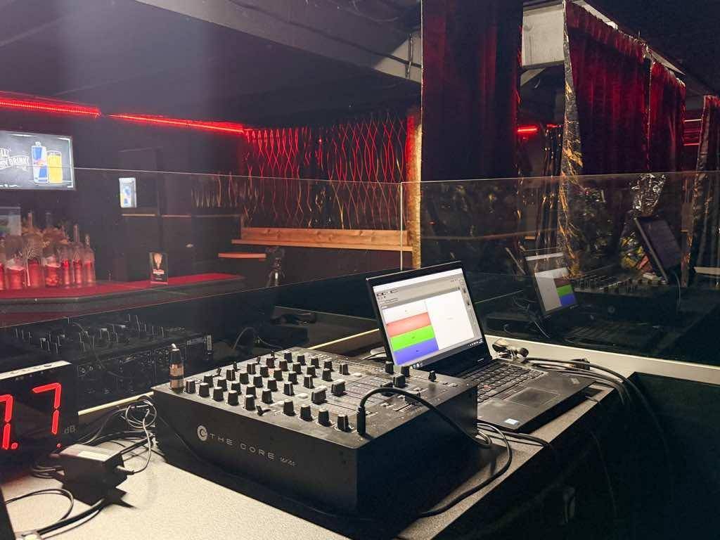 DJ-Pult mit Mischpult, Laptops und Bildschirmen, bereit für musikalische Unterhaltung.