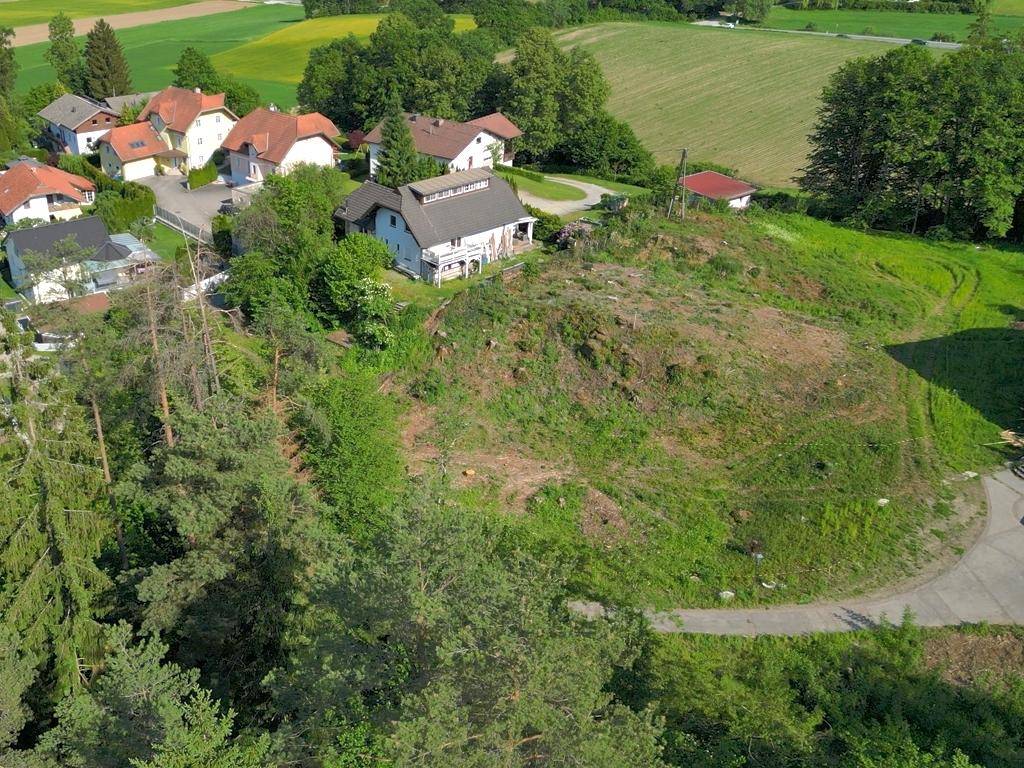 Luftaufnahme eines gerodeten Grundstücks mit einem Haus im Hintergrund und umgebenden Bäumen.