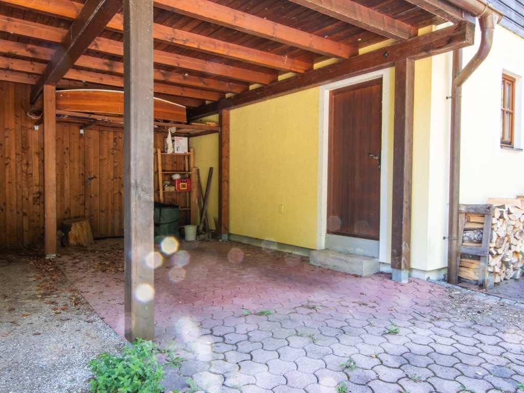 Überdachter Carport-Bereich mit Holzbalkenkonstruktion und Zugang zum Haus.