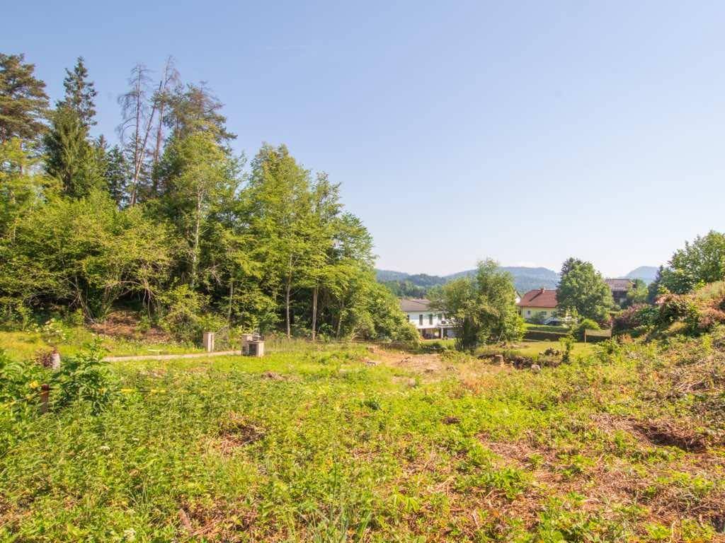 Weitläufiges, unbebautes Grundstück mit Blick auf umliegende Wälder, Häuser und ferne Berge.