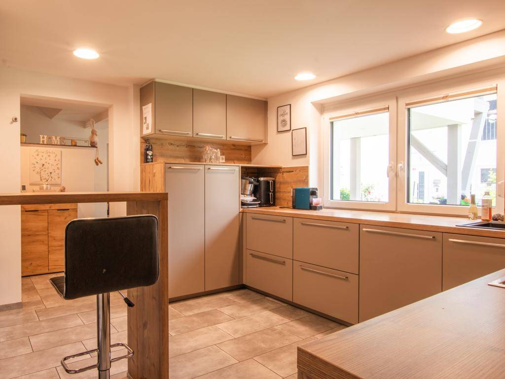 Helle Küche mit Frühstücksbar, integriertem Kühlschrank und Blick in den Flur.