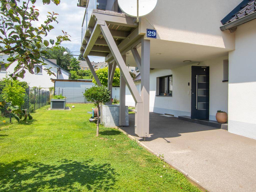 Seitenansicht des Hauses mit überdachtem Eingangsbereich und kleinem Rasenstück.