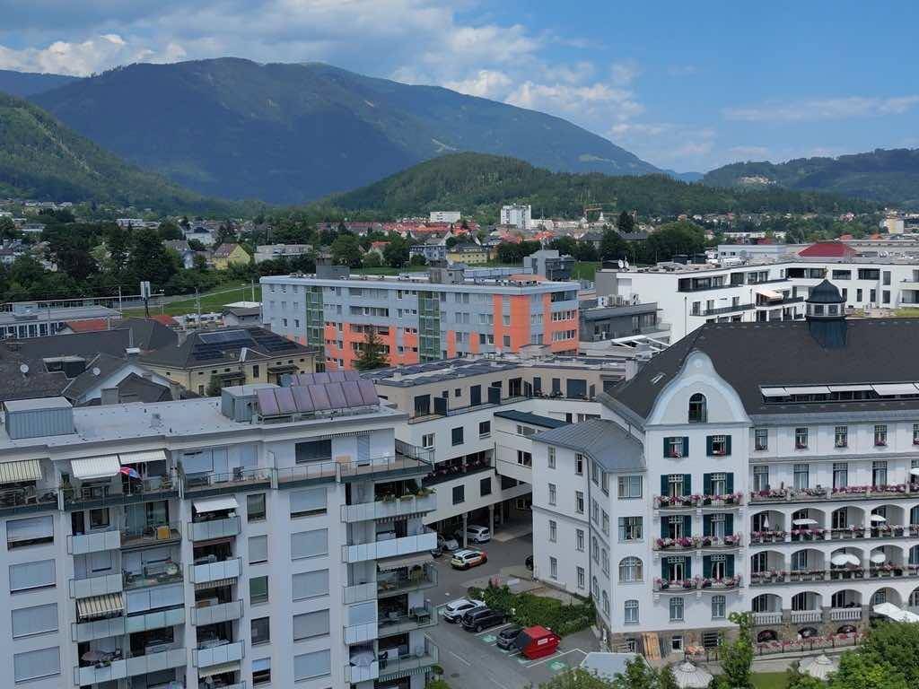 Weitläufige Luftaufnahme der Stadt mit vielfältiger Architektur und majestätischer Bergkulisse.