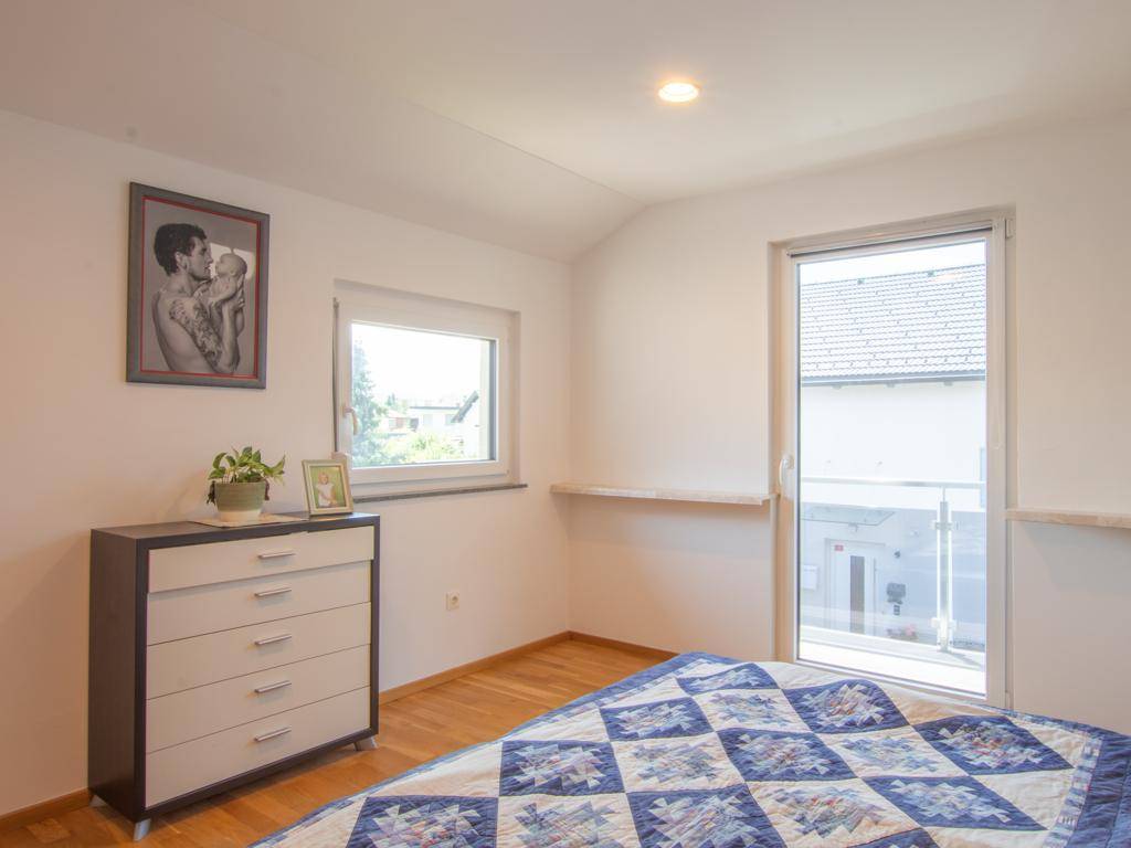 Schlafzimmer mit Holzboden und Zugang zu einem Balkon, der einen Blick auf die Umgebung bietet.