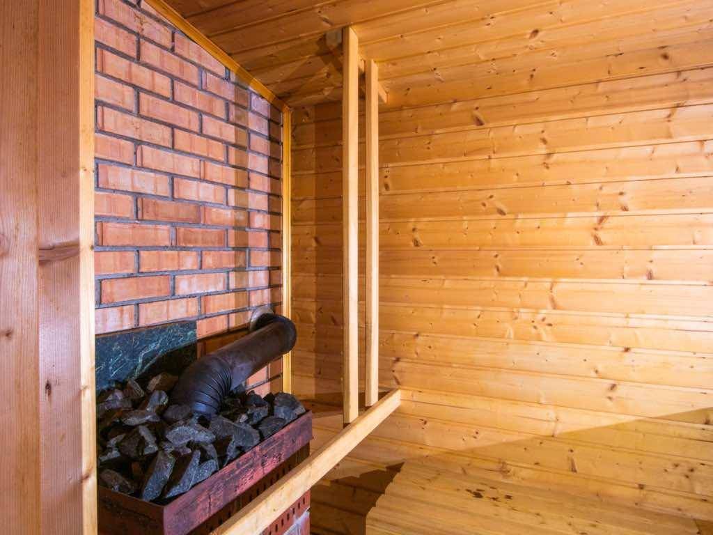 Gemütliche Sauna mit Holzwänden und einem traditionellen Saunaofen aus Ziegelstein.