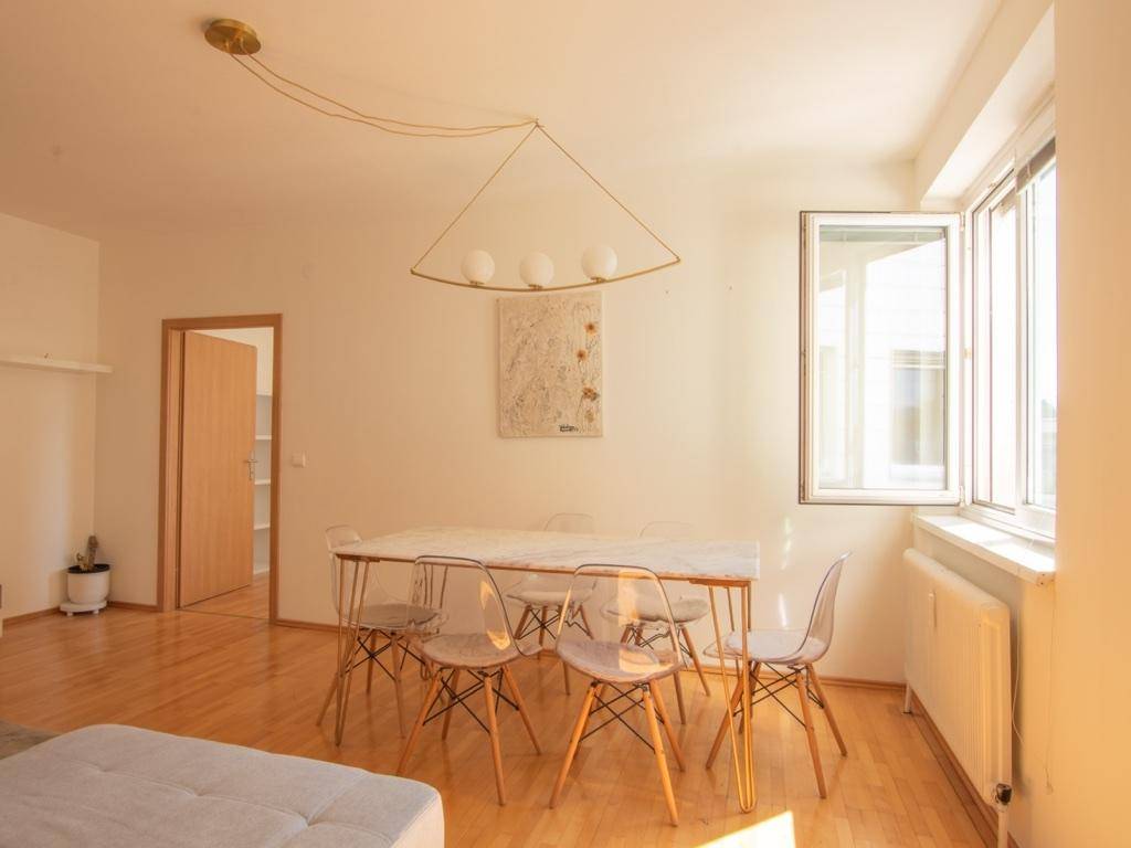 Lichtdurchfluteter Essbereich mit Holzboden und modernem Beleuchtungskörper.