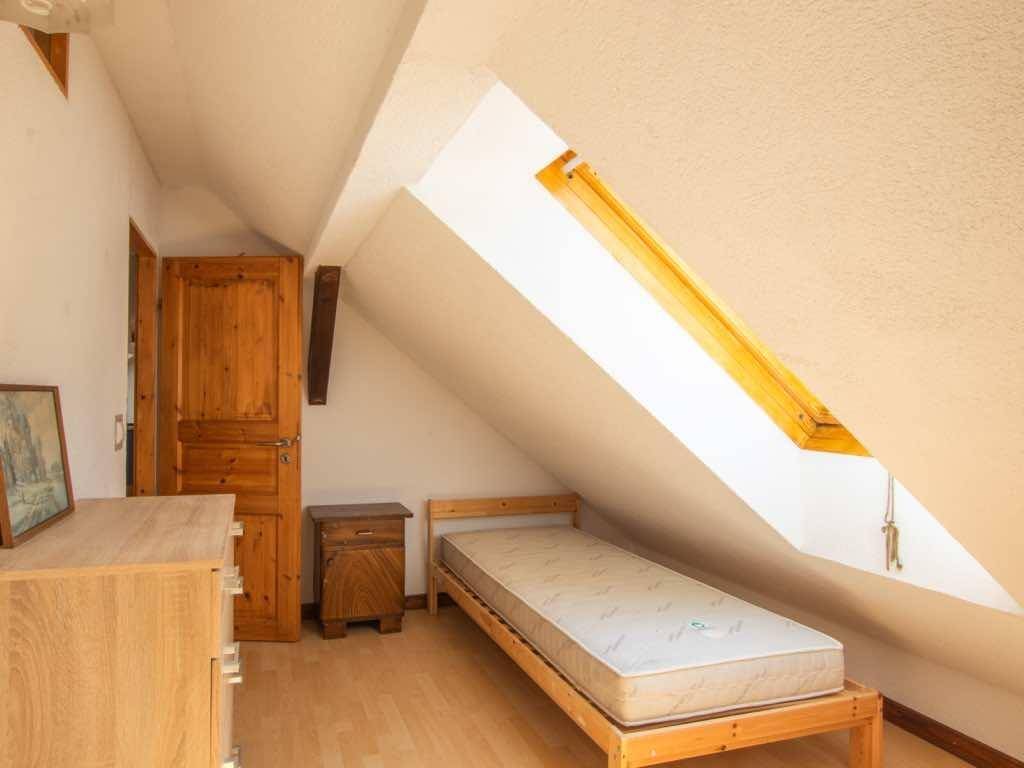 Schlafzimmer im Dachgeschoss mit Holzboden, Einzelbett, Kommode und einem Dachfenster.