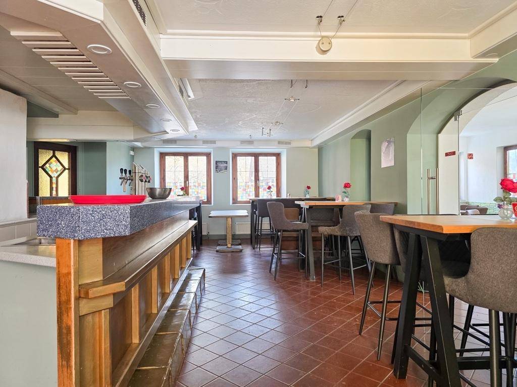 Geräumiger Gastraum mit Bar, hohen Decken und Terrakottafliesen, bereit für Gäste.