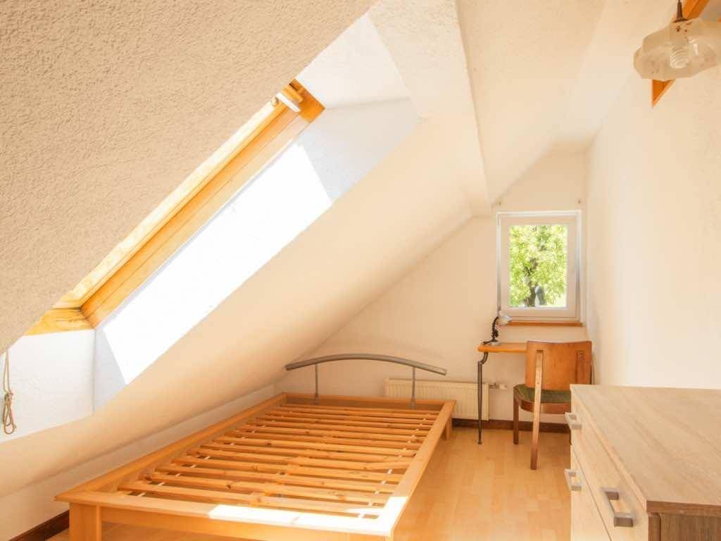 Gemütliches Schlafzimmer im Dachgeschoss mit Holzboden, Einzelbett und einem hellen Dachfenster.