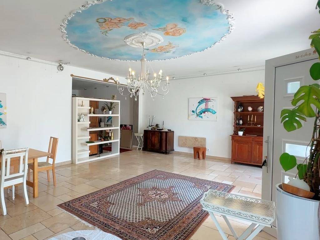 Geräumiger Wohn- und Essbereich mit Fliesenboden, Kronleuchter und kunstvoller Deckenmalerei.