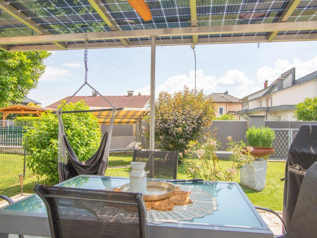 Detailansicht der überdachten Terrasse mit Esstisch, Hängesessel und Blick in den Garten.