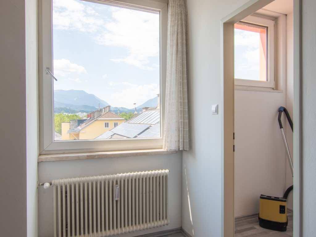 Heller Flurbereich mit Fenster, das einen weiten Blick auf die Berge und Dächer der Stadt bietet.