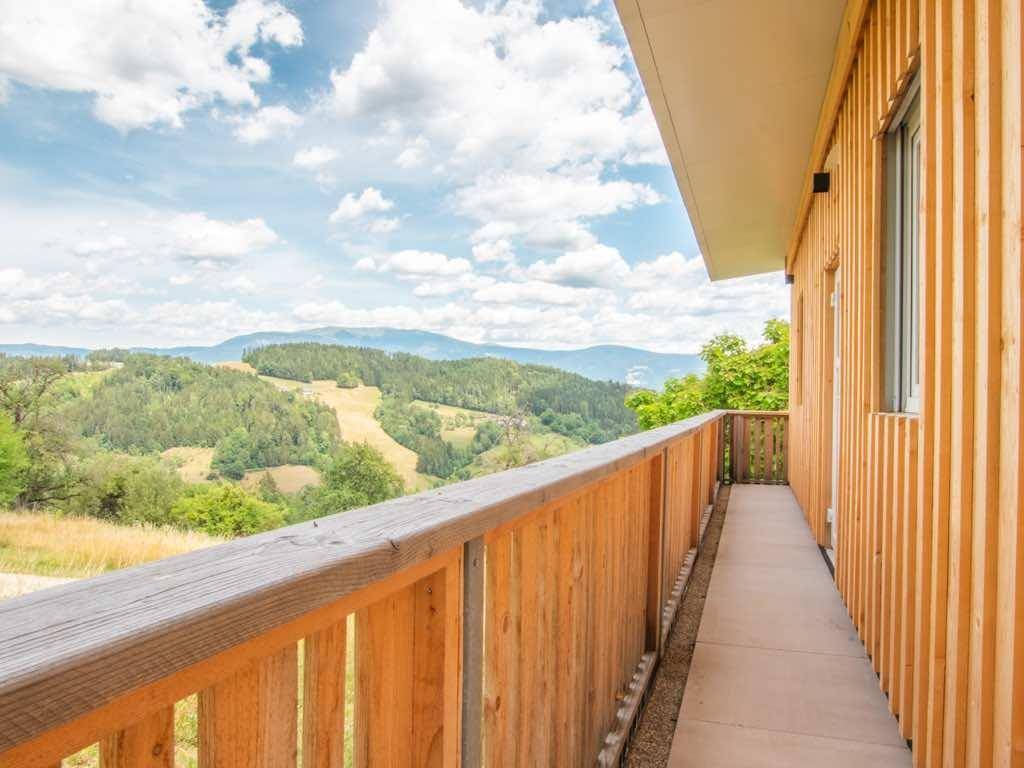 Langer Holzbalkon entlang eines modernen Holzgebäudes mit weitem Blick in die Natur.