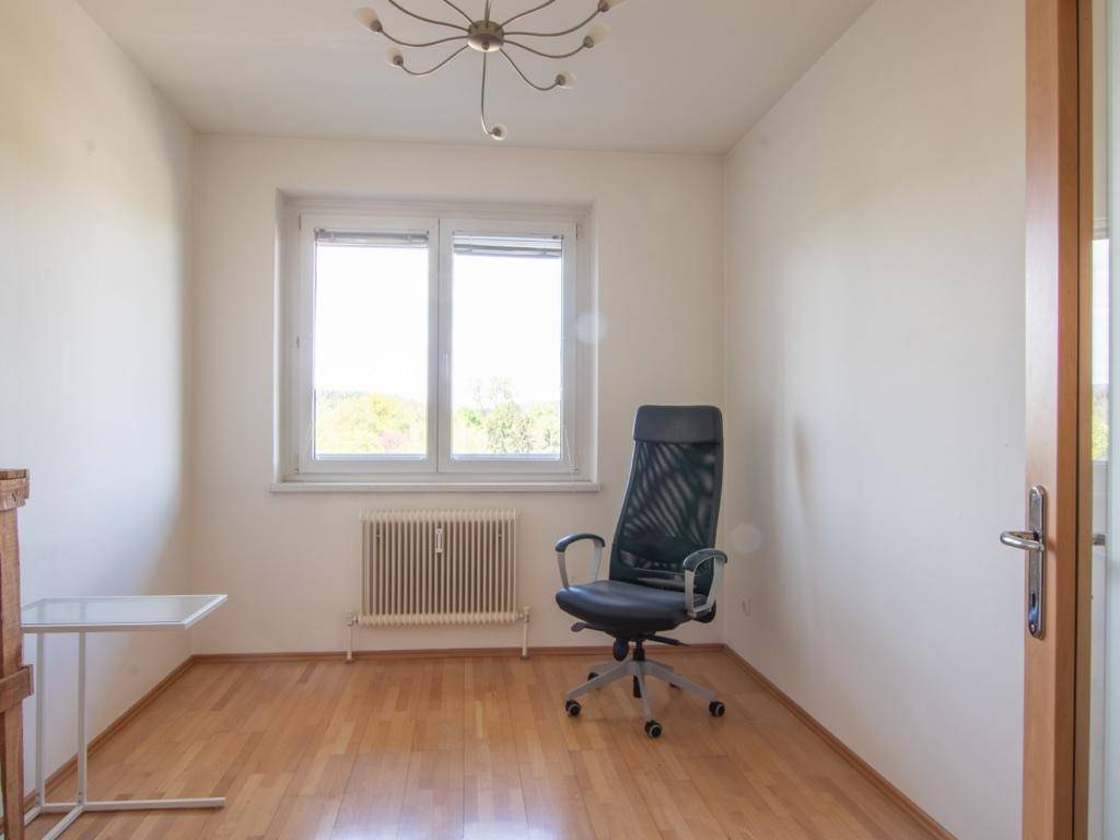 Helles Arbeitszimmer mit Parkettboden, großem Fenster und Blick ins Grüne.