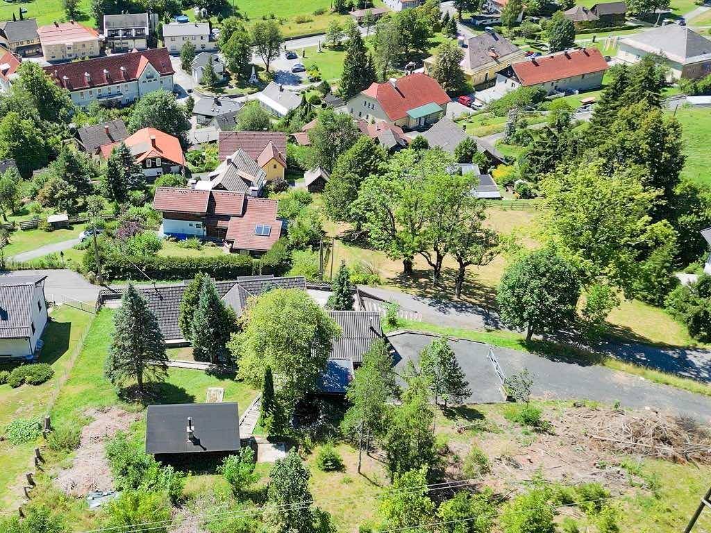 Luftaufnahme einer Wohnsiedlung mit verschiedenen Häusern, Gärten und Baumbestand in ländlicher Umgebung.