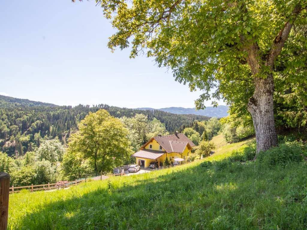 Idyllisches Haus in sonniger Hanglage, umgeben von grünen Wäldern und sanften Hügeln.