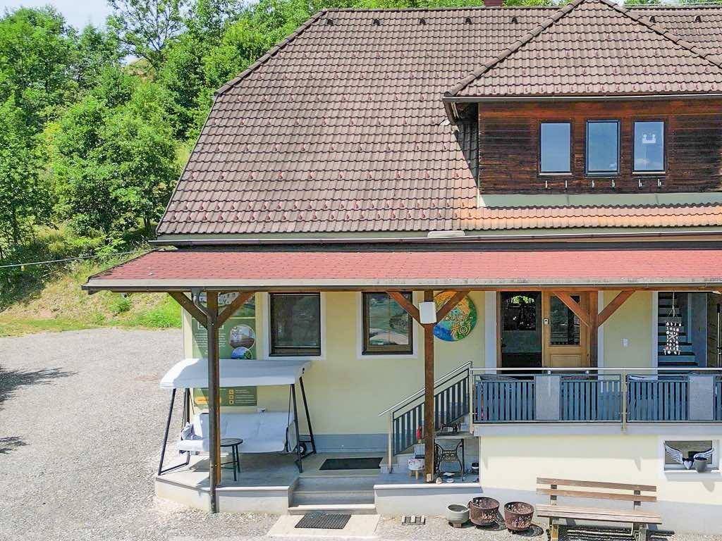 Ansicht des Hauses mit überdachtem Eingangsbereich, Balkon und traditionellem Ziegeldach.