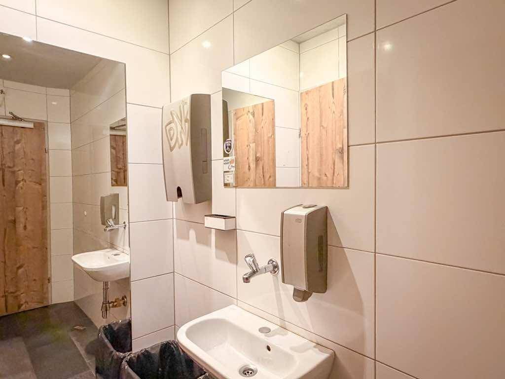 Modernes Badezimmer mit weißen Fliesen, zwei Waschbecken und großen Spiegeln.