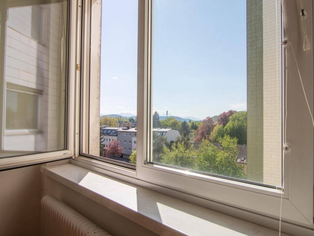 Weitblick aus dem Fenster über die Stadt und die umliegende Landschaft mit Bergen.