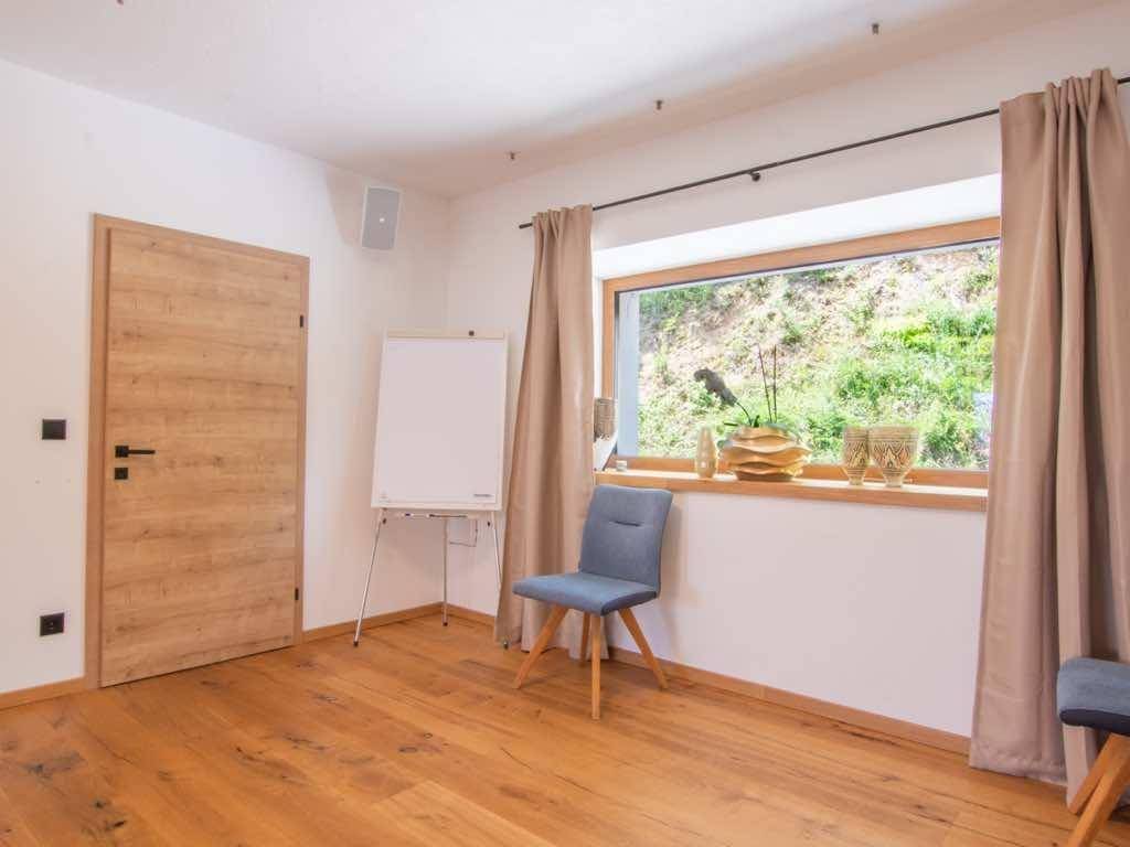 Heller Raum mit Holzboden, großem Fenster und Blick ins Grüne, ideal als Büro oder Seminarraum.