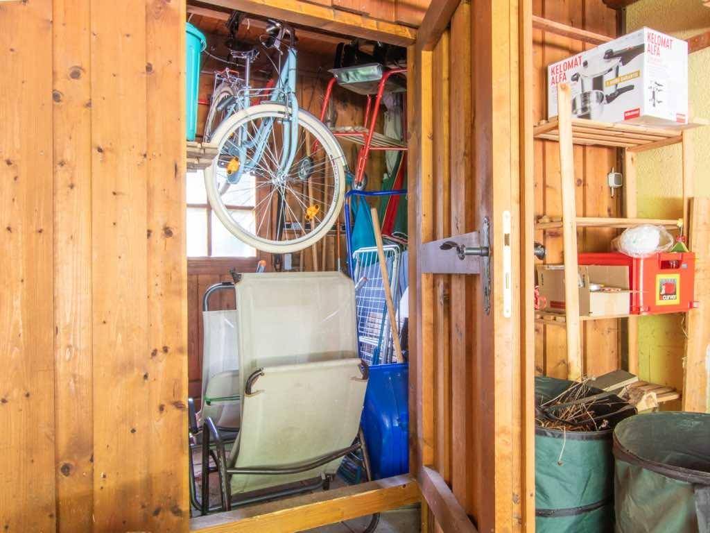 Geräumiger Abstellraum mit Holzverkleidung, Regalen und Platz für Fahrräder und Gartenmöbel.