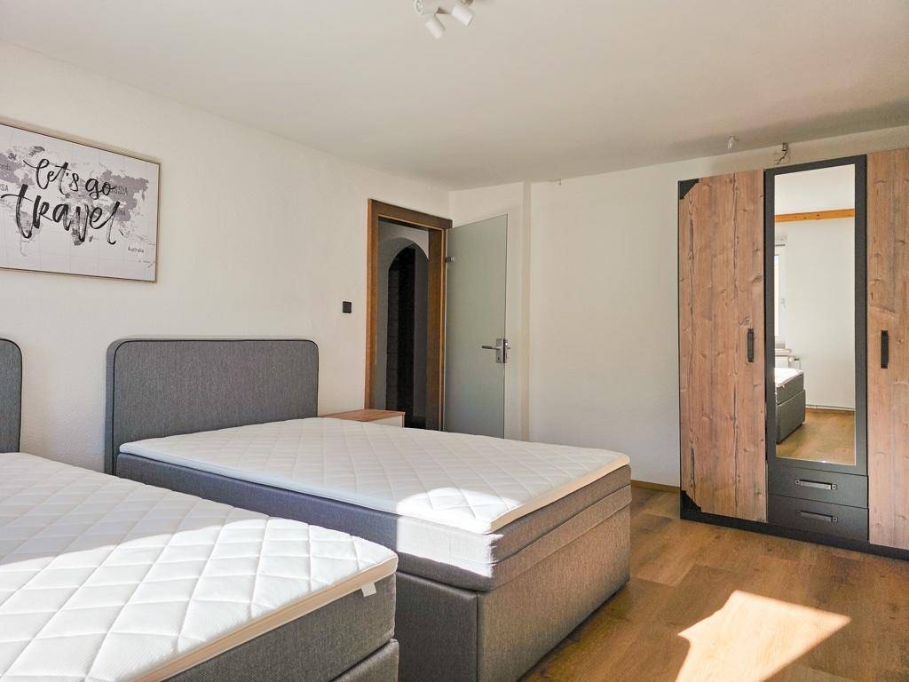 Helles Schlafzimmer mit zwei Einzelbetten, Holzschrank und modernem Dekor.