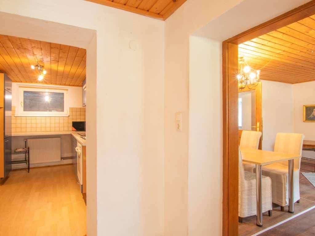 Flur mit Durchgängen zur Küche und zum Essbereich, alles unter einer Holzdecke.