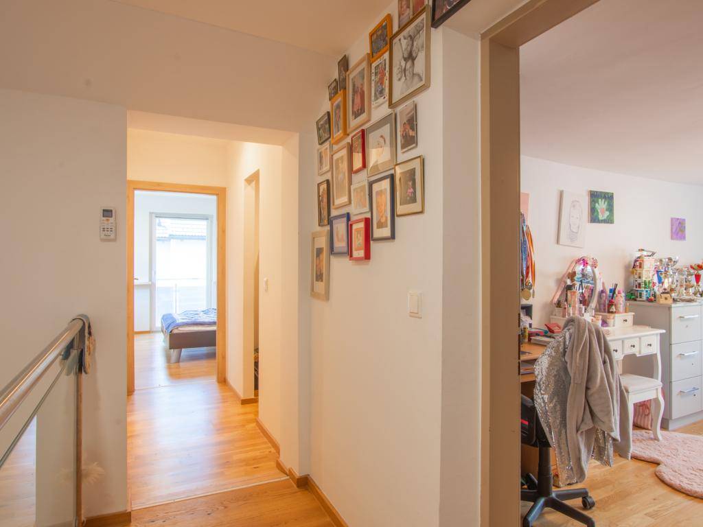 Heller Flur mit Bildergalerie an der Wand und Blick in angrenzende Räume.