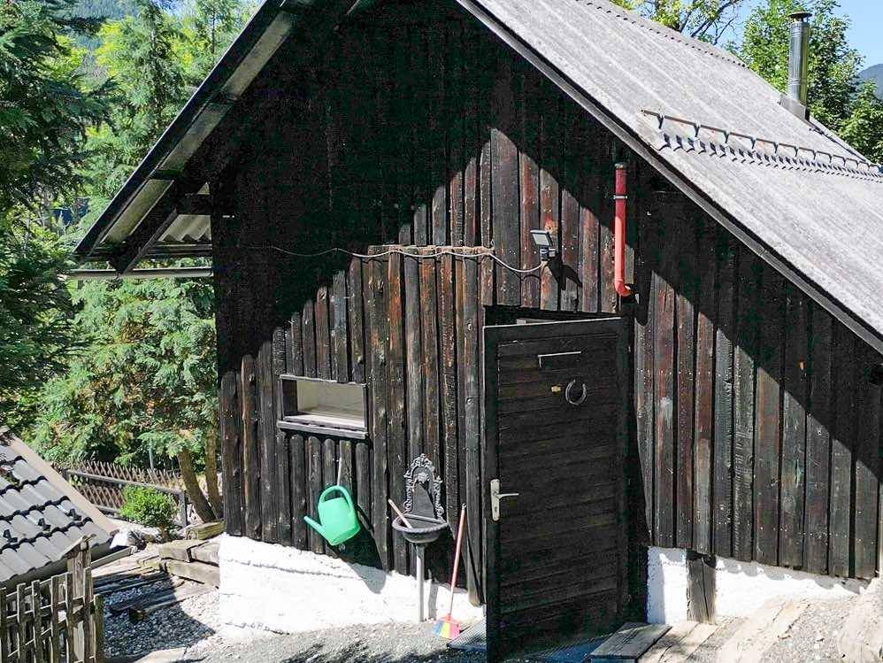 Rustikales Holzgebäude mit dunkler Fassade, einer Holztür und einem kleinen Fenster.