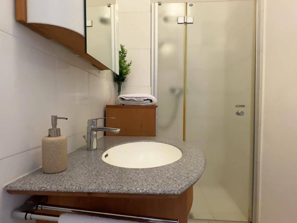 Badezimmer mit modernem Waschbecken, Spiegelschrank und Duschkabine.