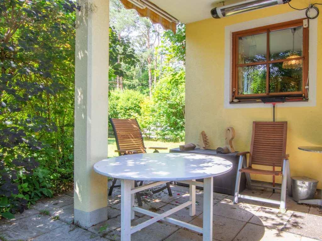 Überdachte Terrasse mit Tisch und Stühlen, ideal für entspannte Stunden im Freien.