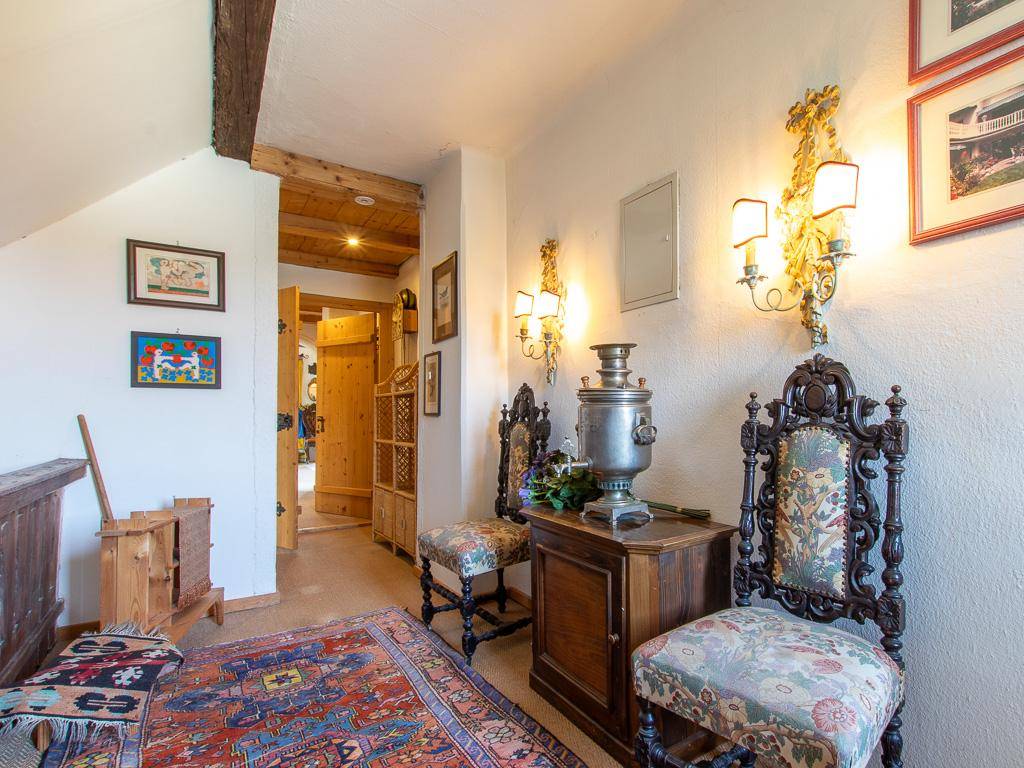 Historischer Flur mit antiken Möbeln, Wandleuchten und sichtbaren Holzbalken an der Decke.