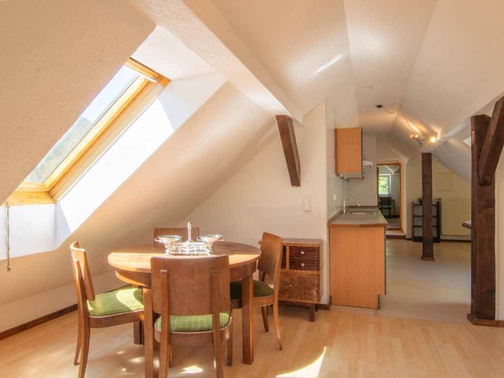 Offener Wohn- und Essbereich im Dachgeschoss mit Küchenzeile, Holzboden und Dachfenster.