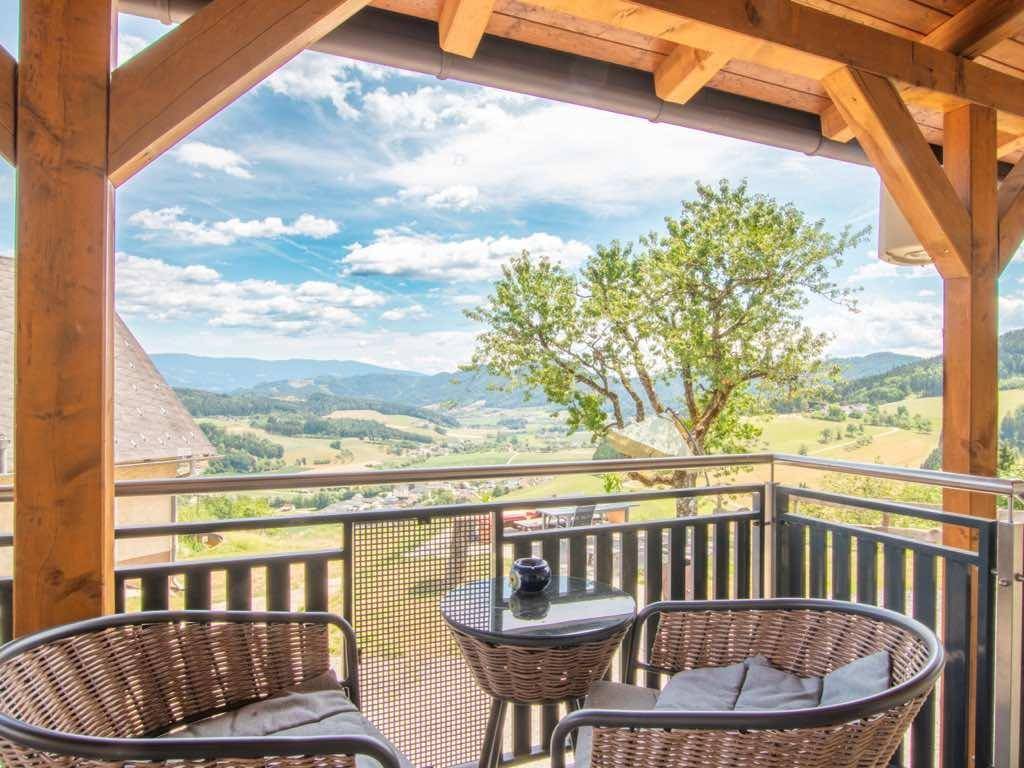 Gemütlicher Balkon mit Korbmöbeln und weitem Blick über das grüne Tal und die Berge.