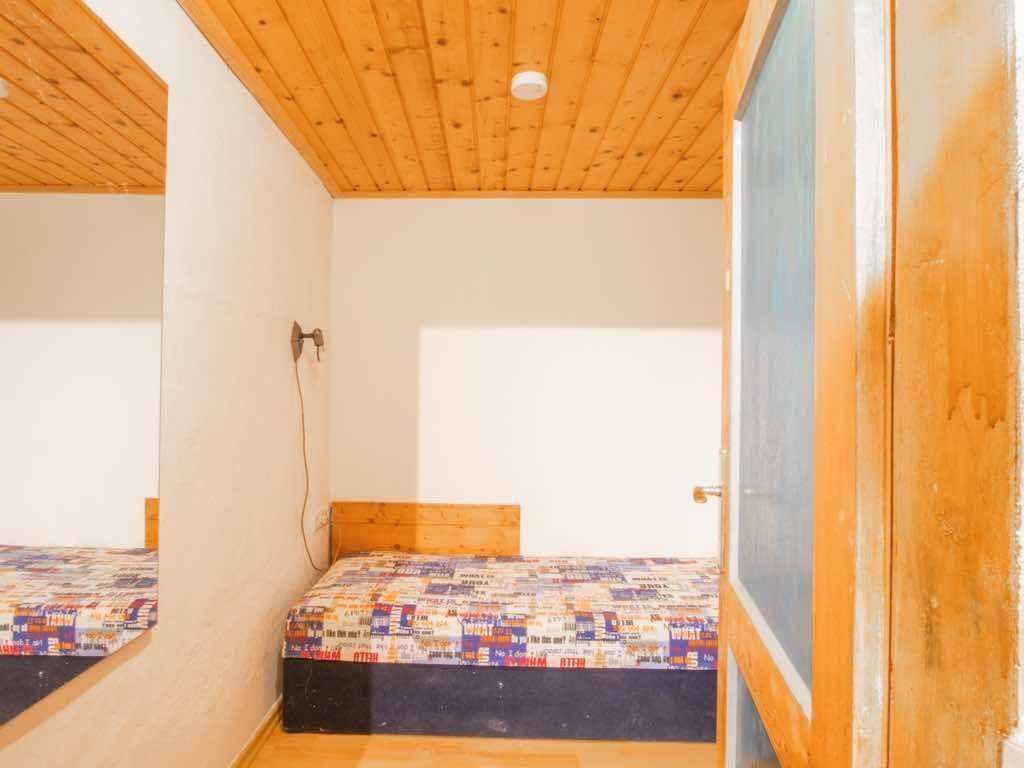 Gemütliches Schlafzimmer mit Bett, großem Spiegel und einer warmen Holzdecke.