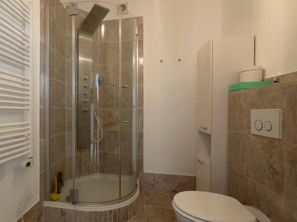 Modernes Badezimmer mit Duschkabine, Wand-WC und beheiztem Handtuchhalter.