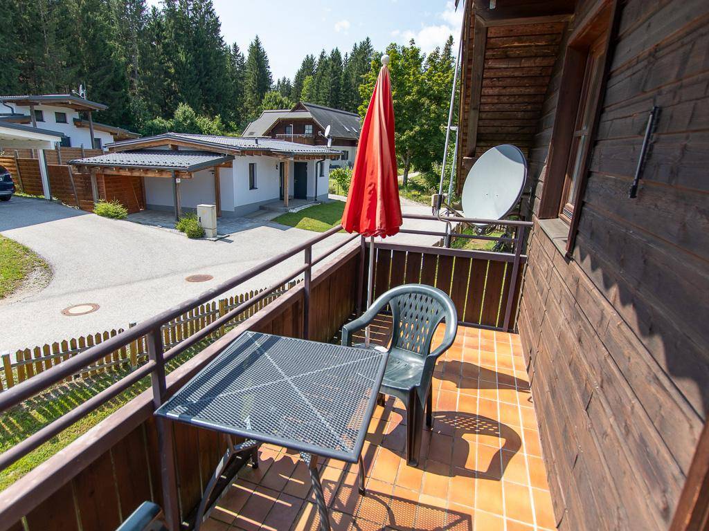 Kleiner Balkon mit Tisch und Stühlen, Blick auf die Zufahrt und umliegende Häuser.