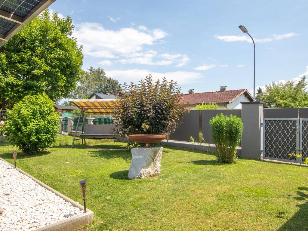 Ruhiger Gartenbereich mit Schaukel, dekorativem Stein und gepflegtem Rasen.