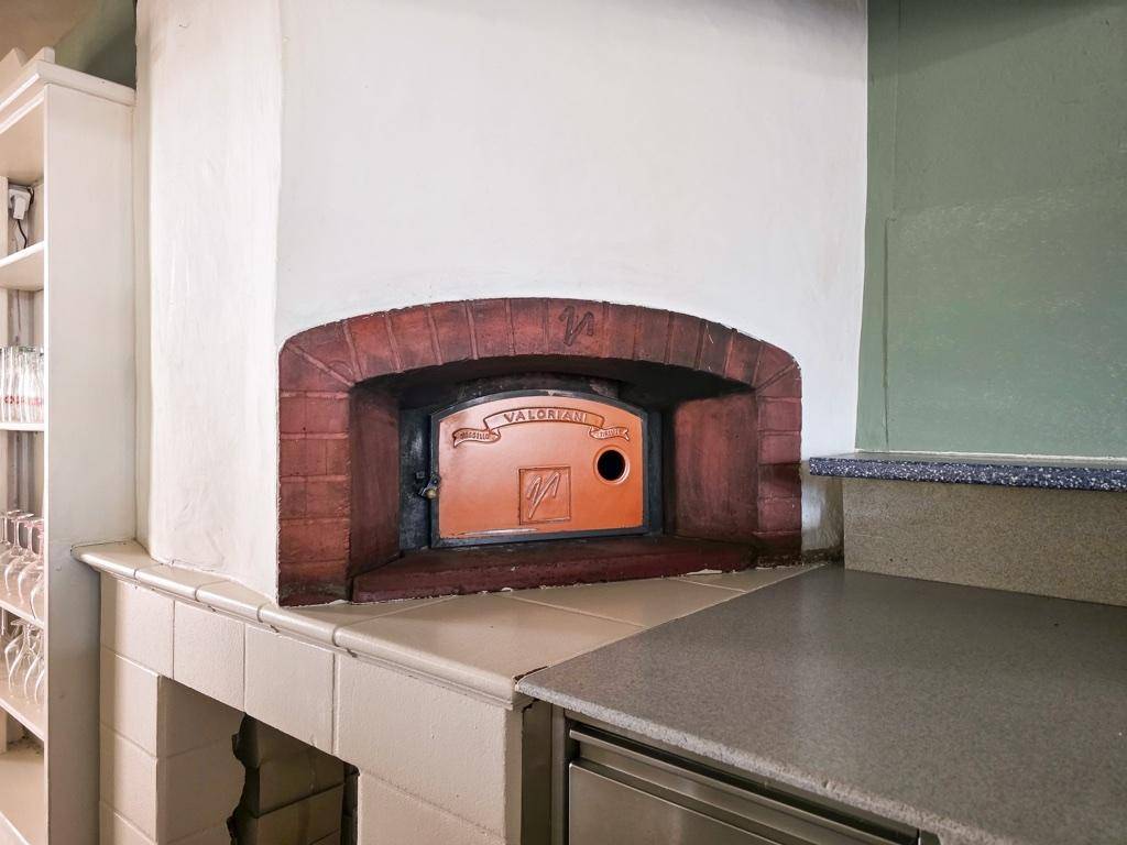 Traditioneller Pizzaofen mit Ziegelverkleidung in einer professionellen Küchenumgebung.