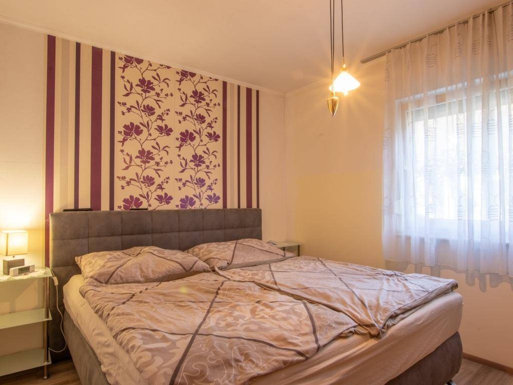 Schlafzimmer mit Doppelbett und dekorativer floraler Tapete an einer Akzentwand.