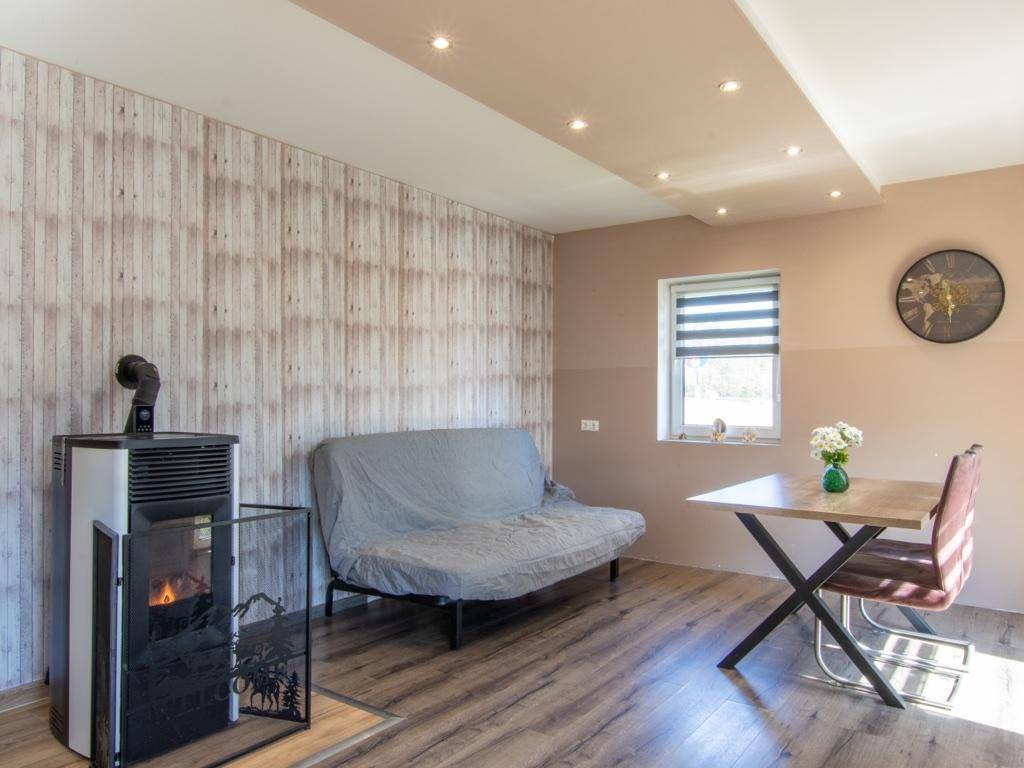 Gemütliches Wohnzimmer mit modernem Ofen, Sofa, Esstisch und Holzoptik-Laminatboden.