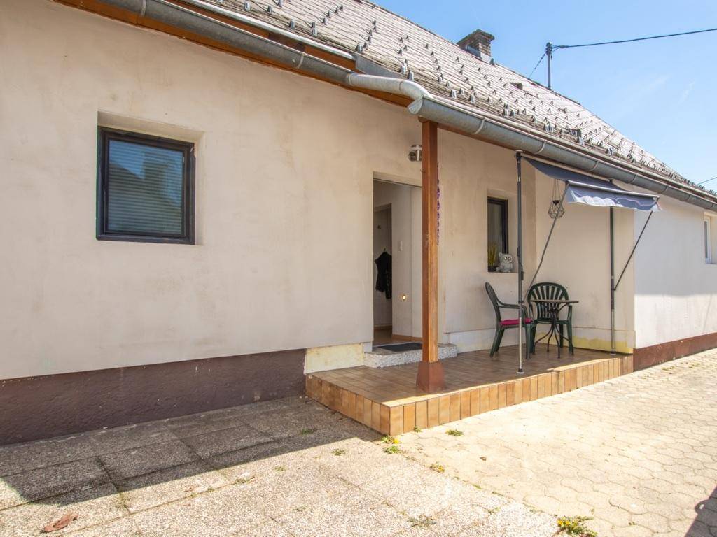 Kleiner gefliester Terrassenbereich am Hauseingang mit Markise und Sitzgelegenheiten.