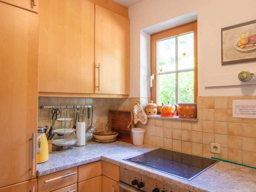 Funktionale Küche mit Holzschränken, Fliesenrückwand und Fenster mit Blick ins Grüne.