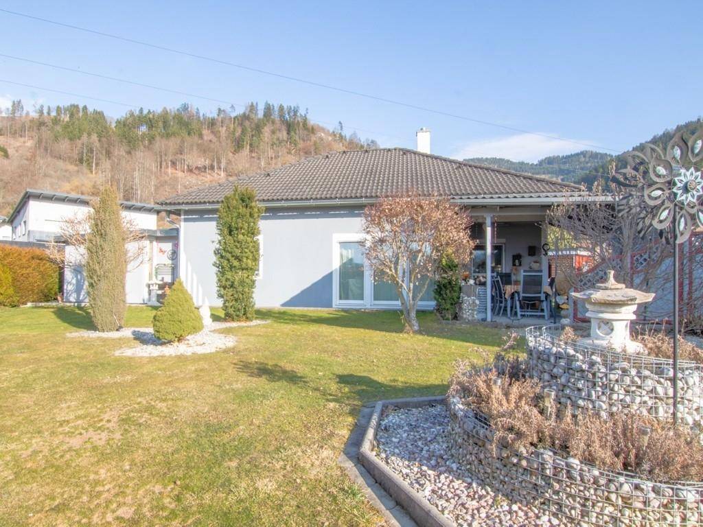 Gepflegter Gartenbereich mit Einfamilienhaus und malerischem Bergblick im Hintergrund.