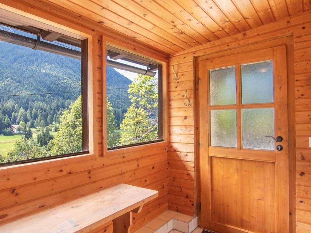 Gemütlicher Wintergarten mit Holzverkleidung, Sitzbank und weitem Blick auf die Berge.