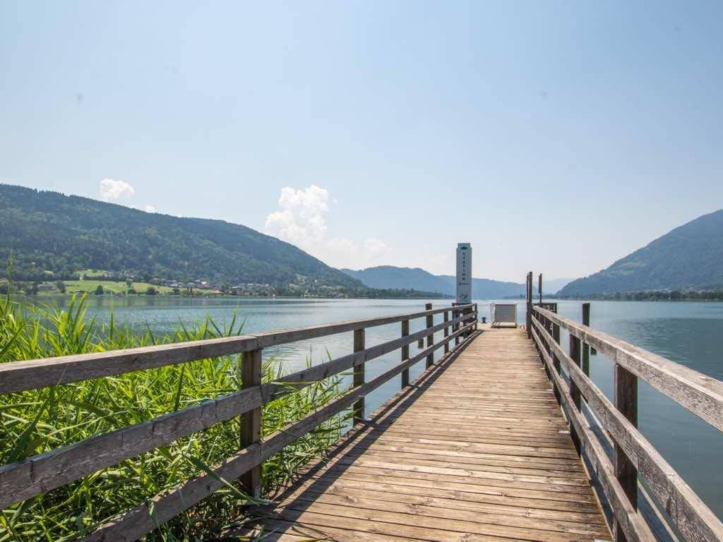 Langer Holzsteg ragt in den klaren See hinein, umgeben von einer beeindruckenden Berglandschaft.