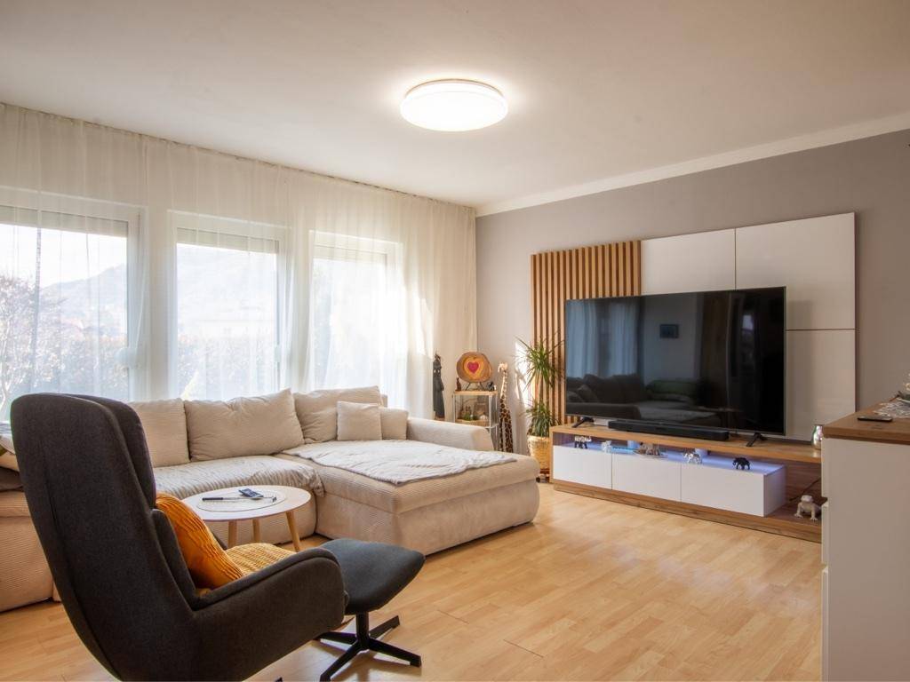 Helles Wohnzimmer mit großem Ecksofa, modernem TV-Möbel und Parkettboden.