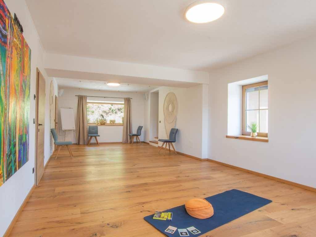 Großer, heller Mehrzweckraum mit Holzboden und Fenstern, ideal für Sport oder Seminare.
