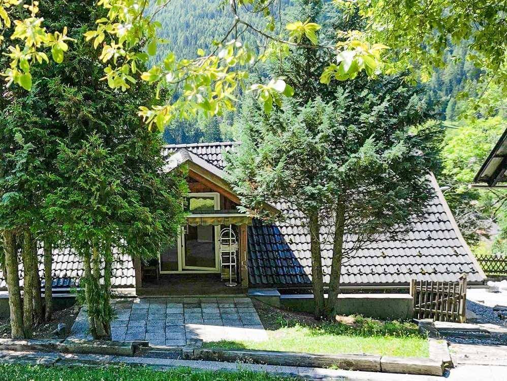 Charmantes Haus mit Satteldach, umgeben von Bäumen und einem gepflegten Vorgartenbereich.