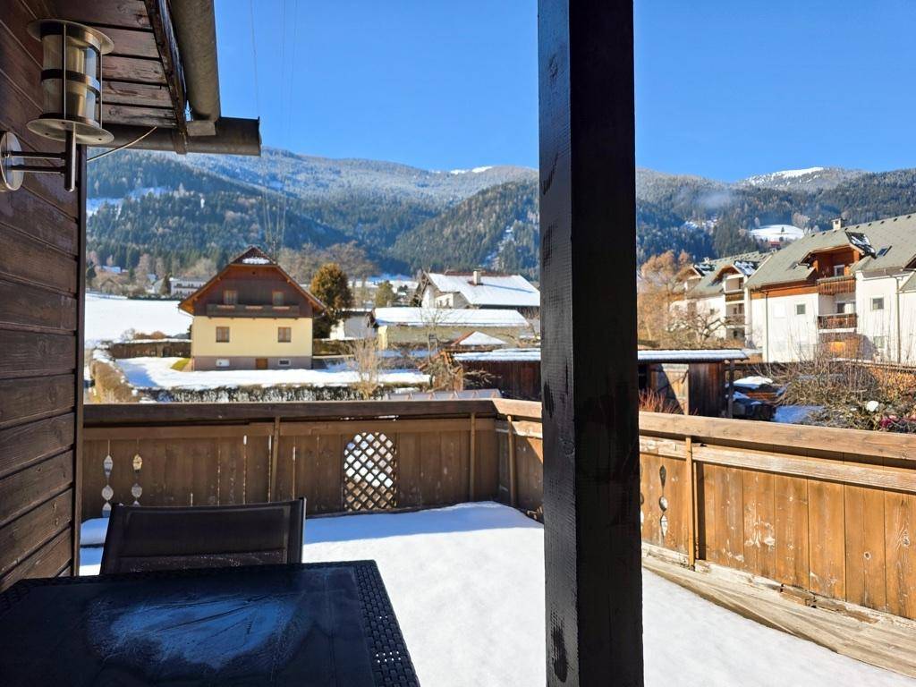 Balkon mit Holzboden, Sitzgelegenheiten und weitem Blick auf die schneebedeckten Berge.